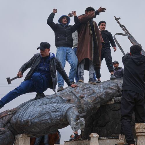 Residents topple a statue of a female Kurdish fighter after the takeover of the town by Syrian government forces from U.S.-backed Syrian Democratic Forces (SDF), in Tabqa, eastern Syria, Sunday, Jan. 18, 2026. (AP Photo/Ghaith Alsayed)