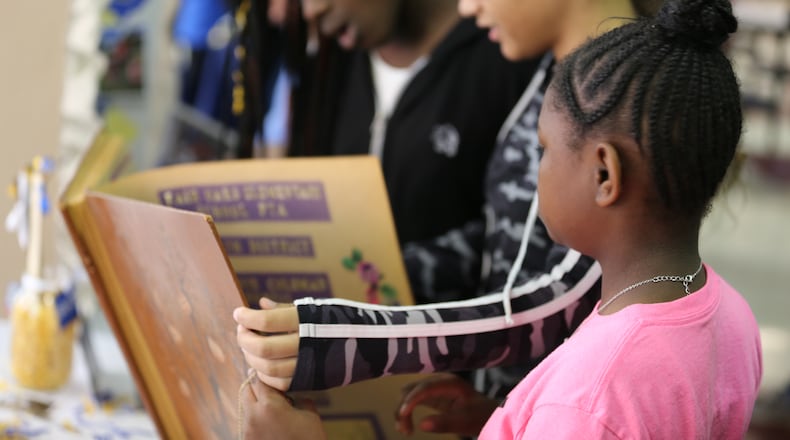 Students look at old photos and books documenting Fair Oaks Elementary School's history during its 60th anniversary celebration.