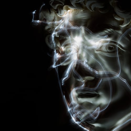 Stefania Terre, who is blind, uses a small light on her fingers while touching a life-size reproduction of the head of Michelangelo's David as she poses for a long-exposure photograph at the Omero Tactile Museum in Ancona, Italy, Thursday, Jan. 15, 2026. (AP Photo/Alessandra Tarantino)