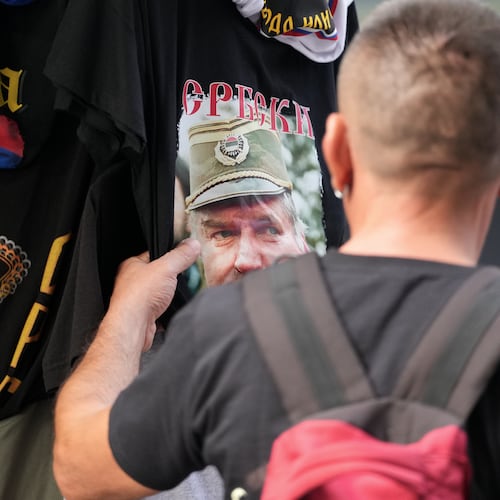 A buyer checks a T-shirt with a picture of former Bosnian Serb wartime general Ratko Mladic displayed on Belgrade's main pedestrian street, Serbia, Friday, Sept. 4, 2026. (AP Photo/Darko Vojinovic)