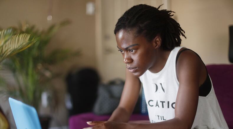 Jessica Melford, at home in her Atlanta apartment, takes an online class in applied behavior analysis offered by her employer, Key Autism Services. As a former ward of the state, Melford benefited from a program that provides financial and other support for former foster children beyond the age of 18. She just graduated from Georgia State and starts grad school Monday. BOB ANDRES / ROBERT.ANDRES@AJC.COM