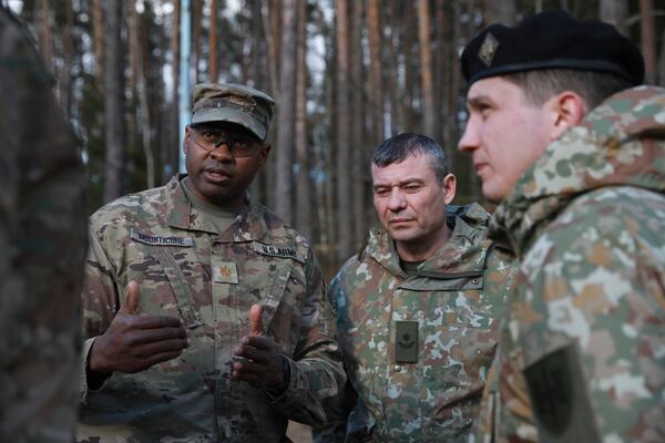 In this image provided by the U.S. Army, U.S. Army soldiers from the 1st Armored Brigade Combat Team, 3rd Infantry Division, along with Lithuanian Army Maj. Nikolaj Kalionovand and emergency services personnel, discuss their plan to recover four U.S. soldiers in a U.S. Army M88 Hercules submerged under several meters of water in a swamp near a training area near Pabadre, Lithuania, Thursday, March 27, 2025. (Trevor Wilson/U.S. Army via AP)