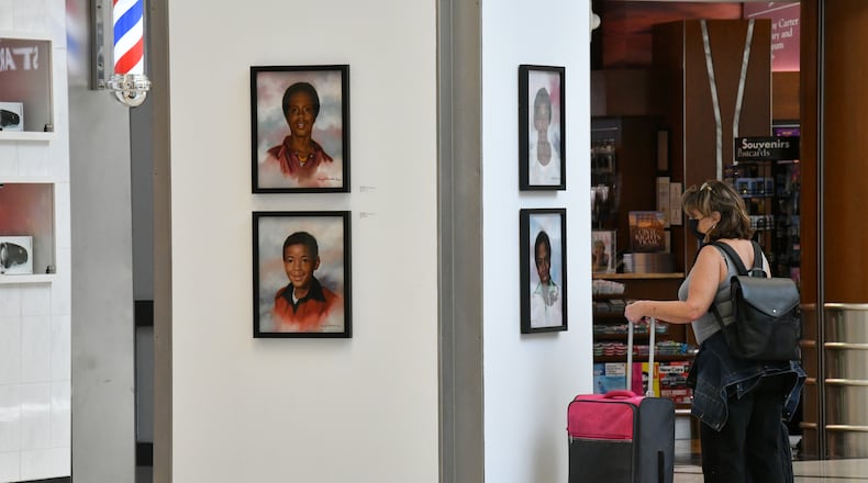 June 30, 2021 Atlanta - Airport travelers appreciate the exhibition of the Atlanta ChildrenÕs Memorial Portraits at Hartsfield-Jackson Atlanta International Airport on Wednesday, June 30, 2021. Hartsfield-Jackson Honors Atlanta Child Murder Victims with Portrait Art Exhibit ATLÕs award-winning art program is hosting the Atlanta ChildrenÕs Memorial Portraits exhibition from June 25 Ð Sept. 8, 2021. Selected from a competition of over 100 regional visual art professionals, artist Dwayne Mitchell was commissioned to create 30 portraits memorializing each victim of the Atlanta Child Murders. (Hyosub Shin / Hyosub.Shin@ajc.com)