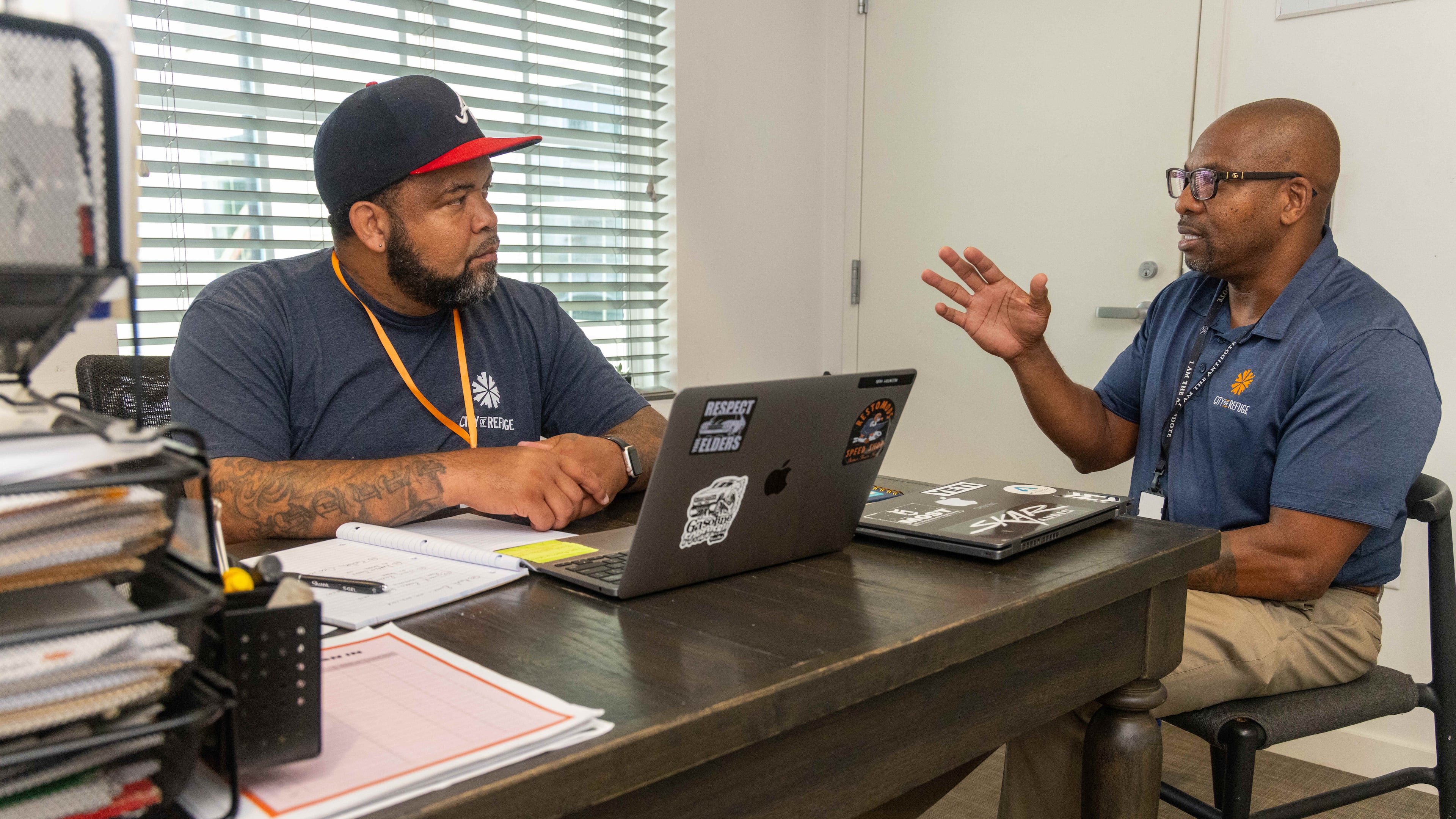 Greg Washington (right) speaks with QuinKnoca Owens, one of the hundreds of individuals helped by the City of Refuge, a faith-based Atlanta nonprofit. Owens spent nearly 30 years in prison and is now the intake coordinator of the 345 housing program. (Phil Skinner for the AJC)