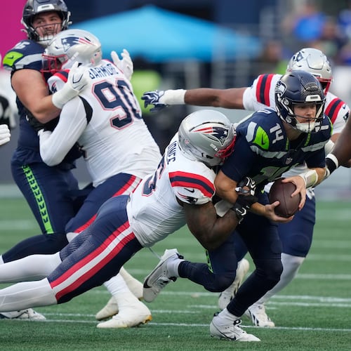Seattle Seahawks quarterback Sam Darnold, center, is sacked by New England Patriots linebacker Dre'mont Jones, left, as Seattle Seahawks linebacker Connor O'Toole is at right, during the first half of an NFL football game, Wednesday, Sept. 9, 2026, in Seattle. (AP Photo/Stephen Brashear)