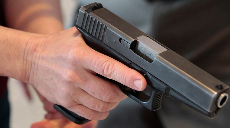 A teacher is shown how to handle a handgun by an instructor during a training session.