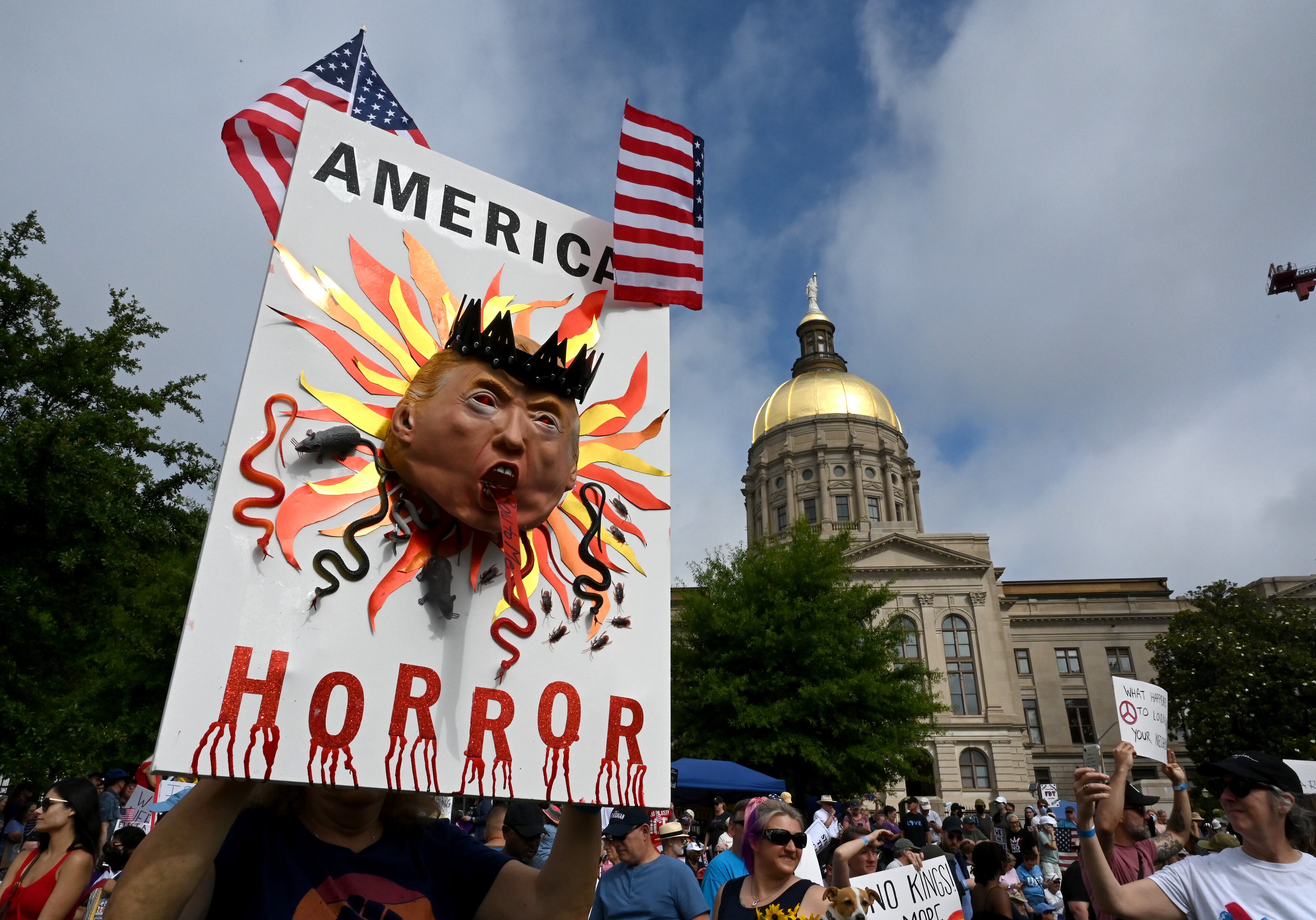 Demonstrators hold signs at Liberty Plaza, near the Georgia Capitol, for a "No Kings" protest to oppose Trump’s immigration policies, Saturday, June 14, 2025, in Atlanta. (Hyosub Shin / AJC)