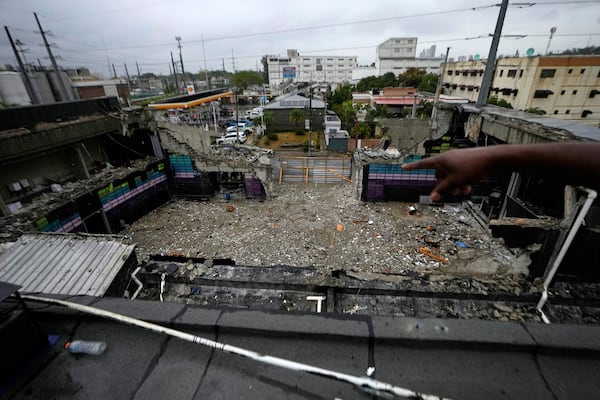 A person points to the inside of the Jet Set nightclub days after its roof collapsed, killing more than 200 people, in Santo Domingo, Dominican Republic, Friday, April 11, 2025. (AP Photo/Matias Delacroix)
