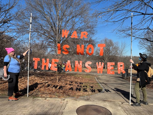 Two people hold up a large sign that reads "WAR IS NOT THE ANSWER" during a rally at Piedmont Park Sunday. (David Aaro/AJC)