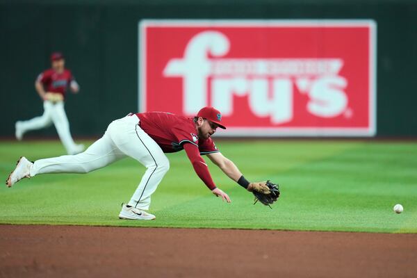 Arizona Diamondbacks second baseman Tim Tawa dives in vain for a run-scoring single hit by Atlanta Braves' Nick Allen during the sixth inning of a baseball game Friday, April 25, 2025, in Phoenix. (AP Photo/Ross D. Franklin)