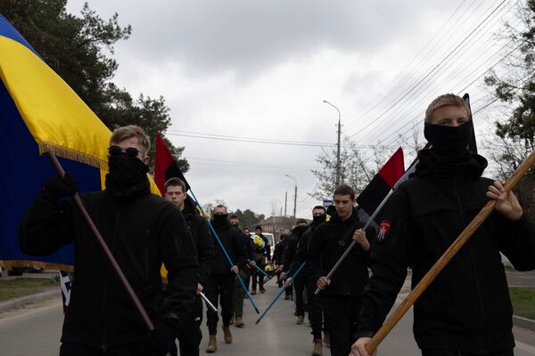 Members of youth nationalist organization "Prava Molod" walk along the road during farewell ceremony of Ukrainian soldier Oleksandr Samoilovich, 18, of 1st Separate Assault Regiment of Dmytro Kotsiubailo, in Slavuta, Ukraine, Friday, April 11, 2025. (AP Photo/Anna Donets)