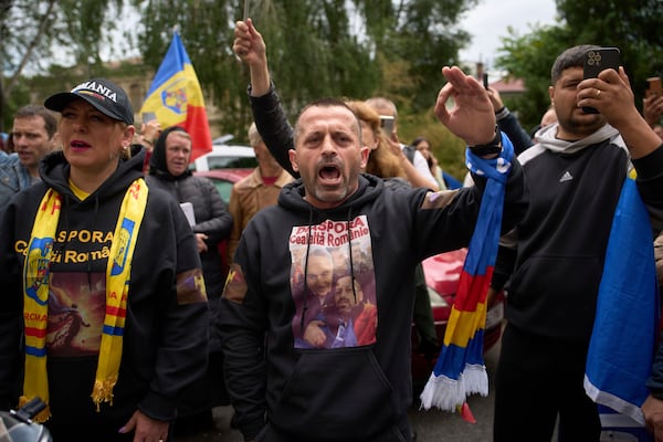 Supporters of Calin Georgescu, the winner of the first round of last year's annulled election, chant slogans during his appearance at a prosecutor's office in Bucharest, Romania, Tuesday, May 27, 2025. (AP Photo/Vadim Ghirda)