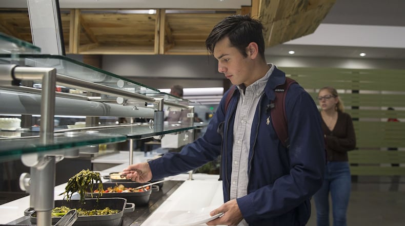 Freshman Will Theodore grabs sauteed spinach and kale from the Stem to Root food bar at the Dobbs Common Table dining hall in the new student center at Emory University. (ALYSSA POINTER / AJC)