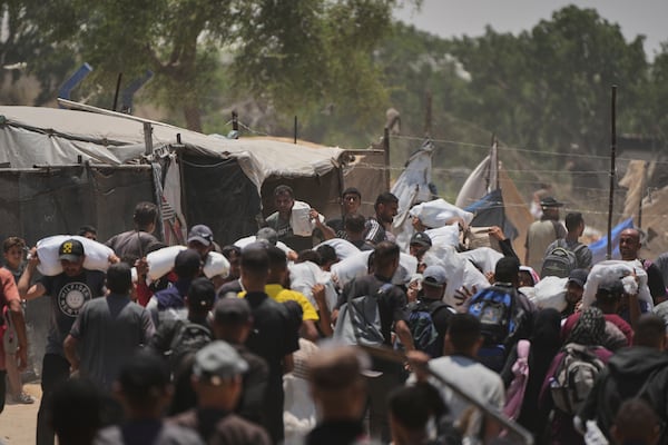 Palestinians carry bags containing food and humanitarian aid packages delivered by the Gaza Humanitarian Foundation, a U.S.-backed organization, in Rafah, southern Gaza Strip, Sunday, June 8, 2025. (AP Photo/Abdel Kareem Hana)