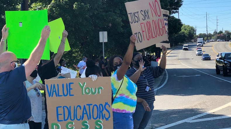 Protesters hold signs outside the DeKalb County School District's Stone Mountain headquarters on July 23, 2020. (Marlon A. Walker / AJC file photo)