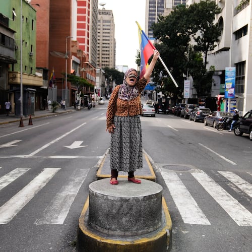 A supporter of Venezuelan President Nicolas Maduro stands on a median strip waving a national flag in Caracas, Venezuela, Saturday, Jan. 3, 2026, after U.S. President Donald Trump announced that Maduro had been captured and flown out of the country. (AP Photo/Ariana Cubillos)