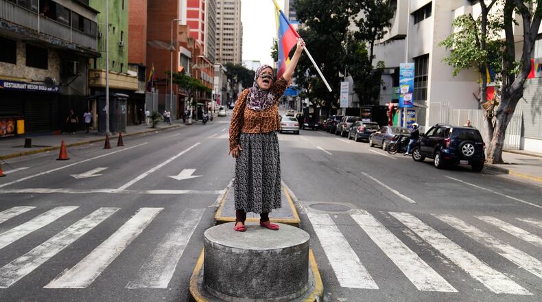 A supporter of Venezuelan President Nicolas Maduro stands on a median strip waving a national flag in Caracas, Venezuela, Saturday, Jan. 3, 2026, after U.S. President Donald Trump announced that Maduro had been captured and flown out of the country. (AP Photo/Ariana Cubillos)