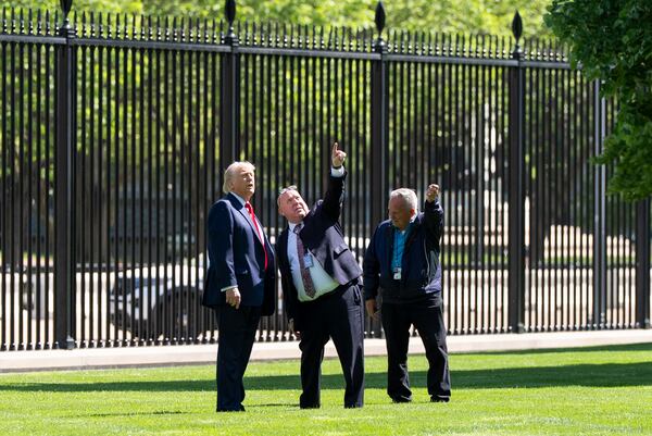 President Donald Trump, left, speaks with Dale Haney, head White House grounds keeper, right, and others, about a new flagpole on the North Lawn of the White House, Wednesday, April 23, 2025, in Washington. (AP Photo/Alex Brandon)