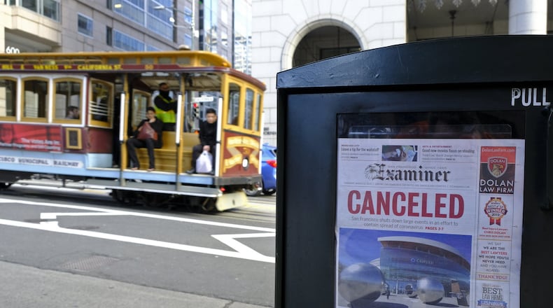 A newspaper headline announcing the closure of large events is displayed Friday, March 13, 2020, in San Francisco. A wave of closures and postponements spanning everything from government offices to cultural events and sports followed concerns of the coronavirus’ spread. (AP Photo/Eric Risberg)
