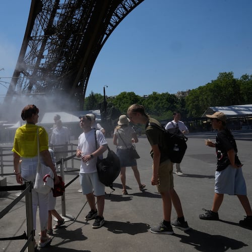 People cool off in a water spray at the Eiffel Tower in Paris, Sunday, June 21, 2026. (AP Photo/Michel Euler)