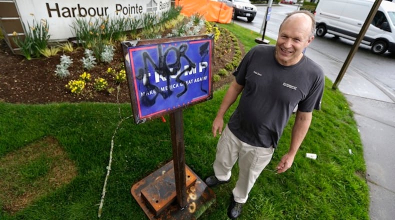 In this April 12, 2016, photo, Peter Zieve, an engineer in Washington state, poses for a photo with campaign signs supporting Donald Trump on his business property that he has had reinforced with metal bases weighing hundreds of pounds after the signs were repeatedly vandalized and tipped over. Zieve loves Trump because "the guy's a person, not a robot. (AP Photo/Ted S. Warren)