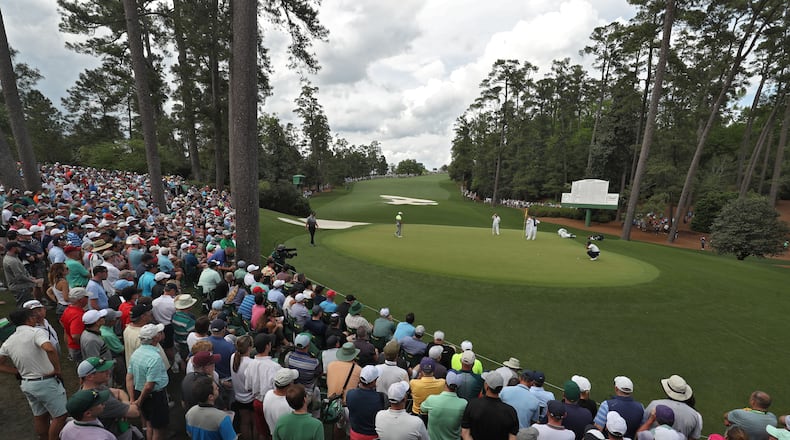A huge gallery congregates around the green on 10 as Tiger Woods putts for a par Friday - a few actually got to see him. (Jason Getz / Special to the AJC)