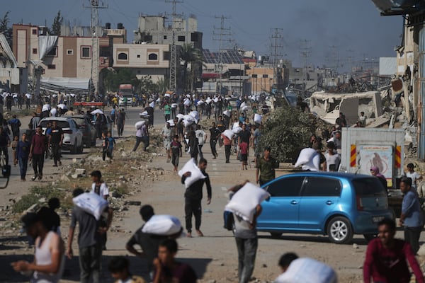 Palestinians carry bags of flour after storming a U.N. World Food Program warehouse in Zawaida, Central Gaza Strip, on Wednesday, May 28, 2025. (AP Photo/Abdel Kareem Hana)