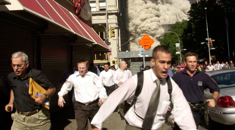 In this Sept. 11, 2001, file photo, people run from the collapse of one of the Twin Towers at the World Trade Center in New York. Stephen Cooper, far left, fleeing smoke and debris as the South Tower crumbled just a block away on Sept. 11, has died from the coronavirus, his family said, according to The Palm Beach Post.