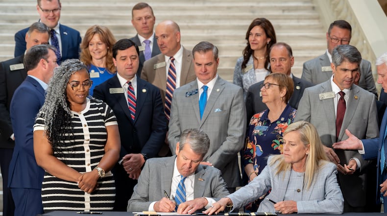 Gov. Brian Kemp signs House Bill 463 on Monday. The law cuts the state income tax rate. (Ben Hendren for the AJC)