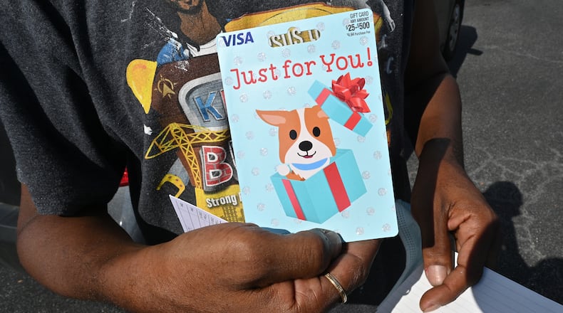 A DeKalb County resident shows off the $100 prepaid debit card he received after he got the COVID-19 vaccine shot during an event at The Gallery at South DeKalb on Saturday, August 13, 2021. (Hyosub Shin / Hyosub.Shin@ajc.com)