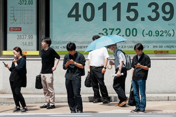 People stand in front of an electronic stock board showing Japan's Nikkei index at a securities firm Tuesday, July 1, 2025, in Tokyo. (AP Photo/Eugene Hoshiko)