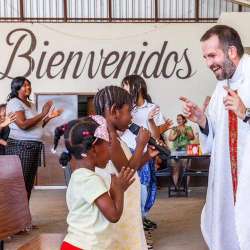 The Rev. Brian Strassburger smiles as Alcala Bouilly sings into the microphone during Mass at Casa del Migrante on Thursday, March 19, 2026, in Reynosa, Mexico. (AP Photo/Michael Gonzalez)