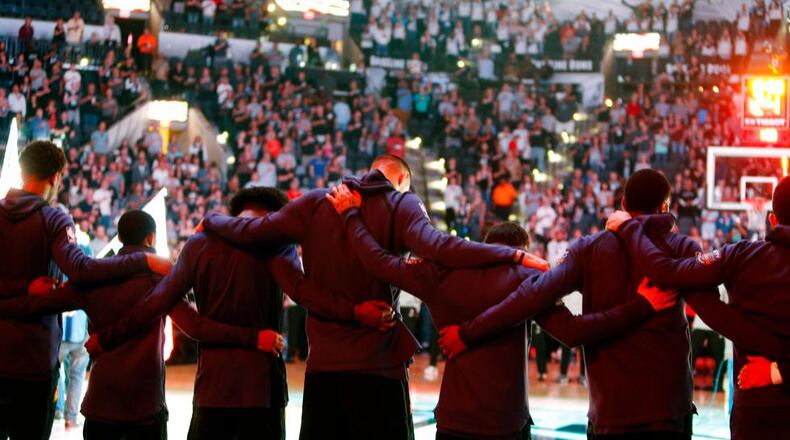 Members of the Phoenix Suns stand arm-in-arm during a moment of silence for the victims of a deadly church shooting in Texas before an NBA basketball game against the San Antonio Spurs, Sunday, Nov. 5, 2017 in San Antonio. (AP Photo/Ronald Cortes)