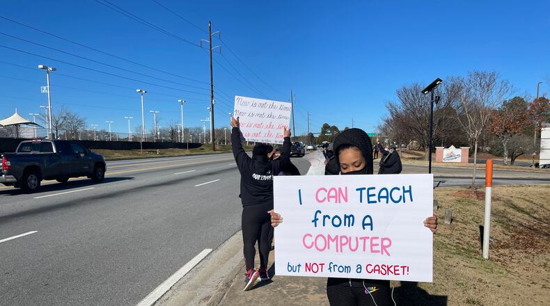 Community members in DeKalb held signs to protest against the reopening of DeKalb County schools.