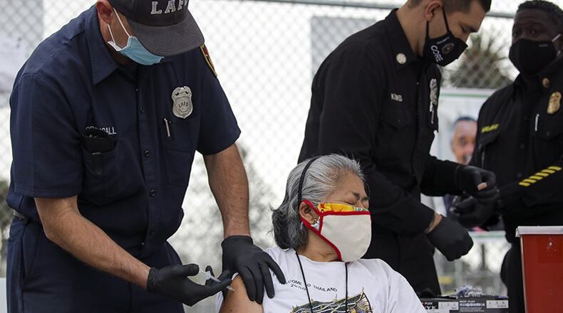 Firefighter Anthony MacDougall administers a COVID-19 vaccine to Carmen Limeta at a mobile vaccination site at South Park Recreation Center in Los Angeles. In Sandy Springs, a mobile vaccine site operated by  Community Organized Relief Effort has opened. (Irfan Khan/Los Angeles Times/TNS)