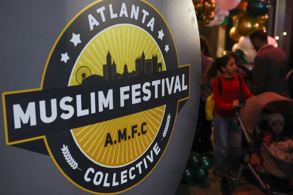 Attendees walk past an Atlanta Muslim Festival Collective sign at the Atlanta Ramadan Food Festival in Norcross on Friday, Feb. 27, 2026. (Arvin Temkar/AJC)