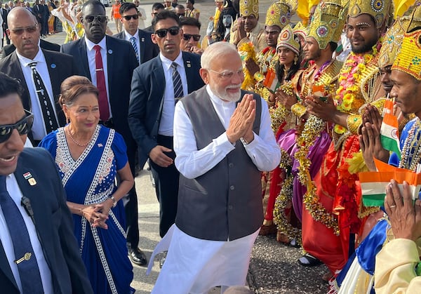 India's Prime Minister Narendra Modi greets people alongside Trinidad and Tobago's Prime Minister Kamla Persad-Bissessar, left, dressed in traditional Indian, at Piarco International Airport in Piarco, Trinidad and Tobago, Thursday, July 3, 2025. (AP Photo/Jermaine Cruickshank)