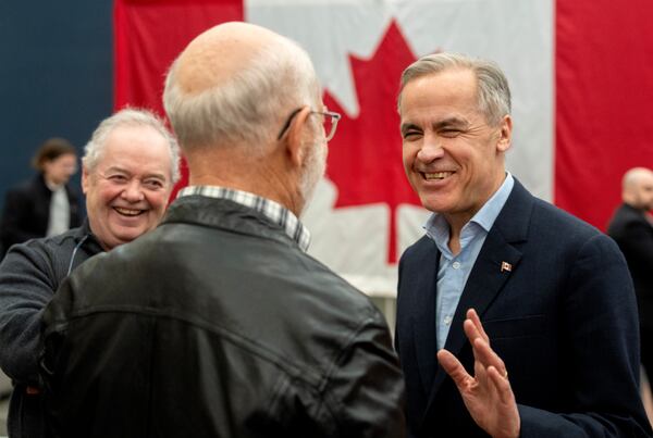 Canada Liberal Leader Mark Carney shares a laugh with residents during a meet and greet at the airport in Gander Newfoundland, on Monday, March 24, 2025. (Frank Gunn/The Canadian Press via AP)