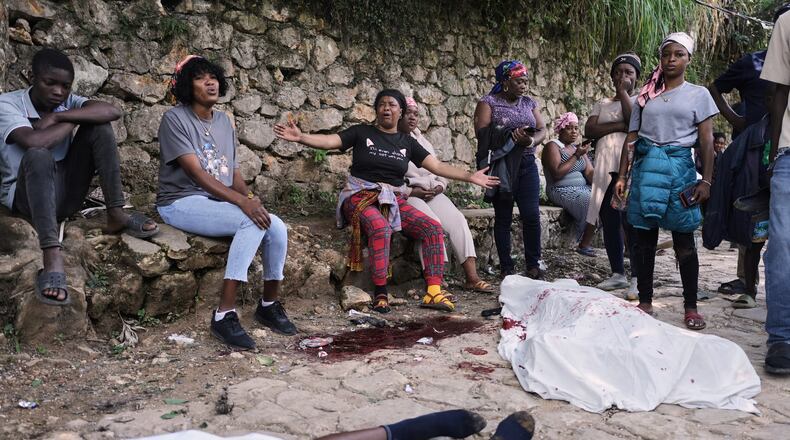 People gather next to the bodies of people they said were their relatives and were killed in a gang attack in the Kenscoff neighborhood of Port-au-Prince, Haiti, Monday, Aug. 24, 2026. (AP Photo/Odelyn Joseph)