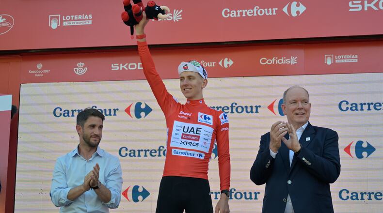 Slovenia's Tadej Pogacar, wearing the overall leader's red jersey celebrates on the podium after the second stage of the La Vuelta cycling race, with start in Monaco and finish in Manosque, France, Sunday, Aug. 23, 2026. (AP Photo/Philippe Magoni)