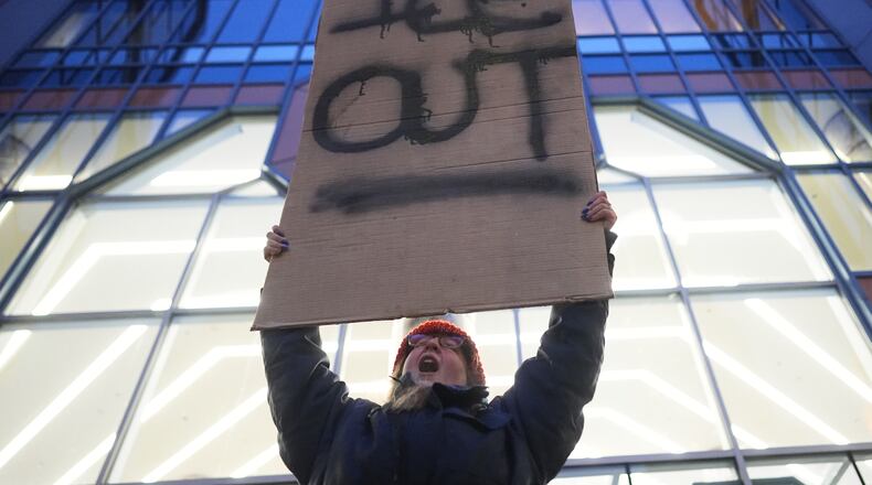 A demonstrator holds a sign reading "ICE OUT" during a protest outside the office of Sen. Amy Klobuchar, D-Minn., on Monday, Jan. 26, 2026, in Minneapolis. (AP Photo/Adam Gray)