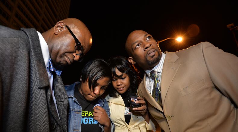 Nov. 24, 2014, Atlanta: (From left) Charles White, national field director of the National Action Network, Tamarre Torchon, with the National Action Network Youth Move, State Rep.-elect Erica Thomas and Atlanta civil rights activist Markel Hutchins listen on a phone Monday, Nov. 24, 2014 outside the Richard B. Russell Federal Building in downtown Atlanta to the announcement of a grand jury's decision not to indict Ferguson police officer Darren Wilson. BRANT SANDERLIN / BSANDERLIN@AJC.COM