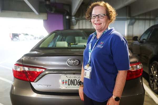 Nancy Epstein poses for a portrait with her specialty Children’s Hospital license plate at the Children’s Healthcare of Atlanta parking garage on Wednesday, July 2, 2025. (Abbey Cutrer / AJC)