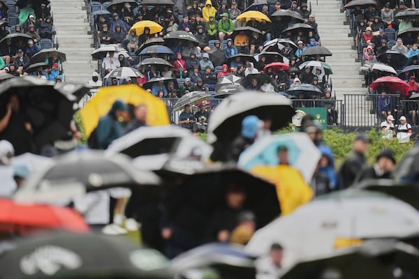 Spectators hold up umbrellas as heat rain falls during the first round of the British Open golf championship at the Royal Portrush Golf Club, Northern Ireland, Thursday, July 17, 2025. (AP Photo/Francisco Seco)