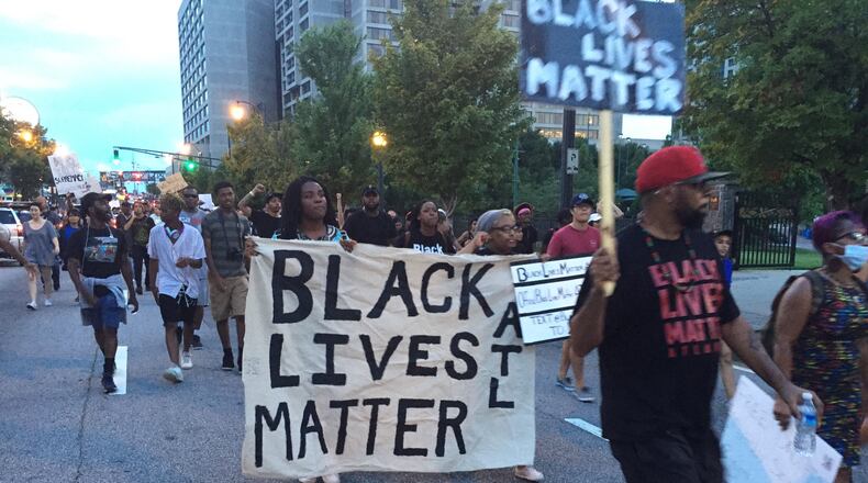 Protesters with signs march in Atlanta Sunday night. It was the fourth straight day of protests in connection with recent police shootings of blacks. (AJC Photo, Jeremy Redmon)