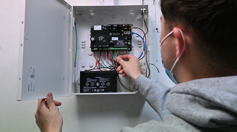 Ethan King, technician with Compass Security Solutions, checks the main alarm panel at a car dealership in Sandy Springs on Thursday, April 22, 2021. (Hyosub Shin / Hyosub.Shin@ajc.com)