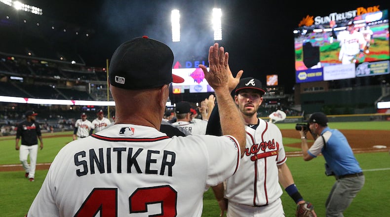 Atlanta Braves manager Brian Snitker shares a post-game high-five with shortstop Dansby Swanson earlier this season. (Curtis Compton/ccompton@ajc.com)