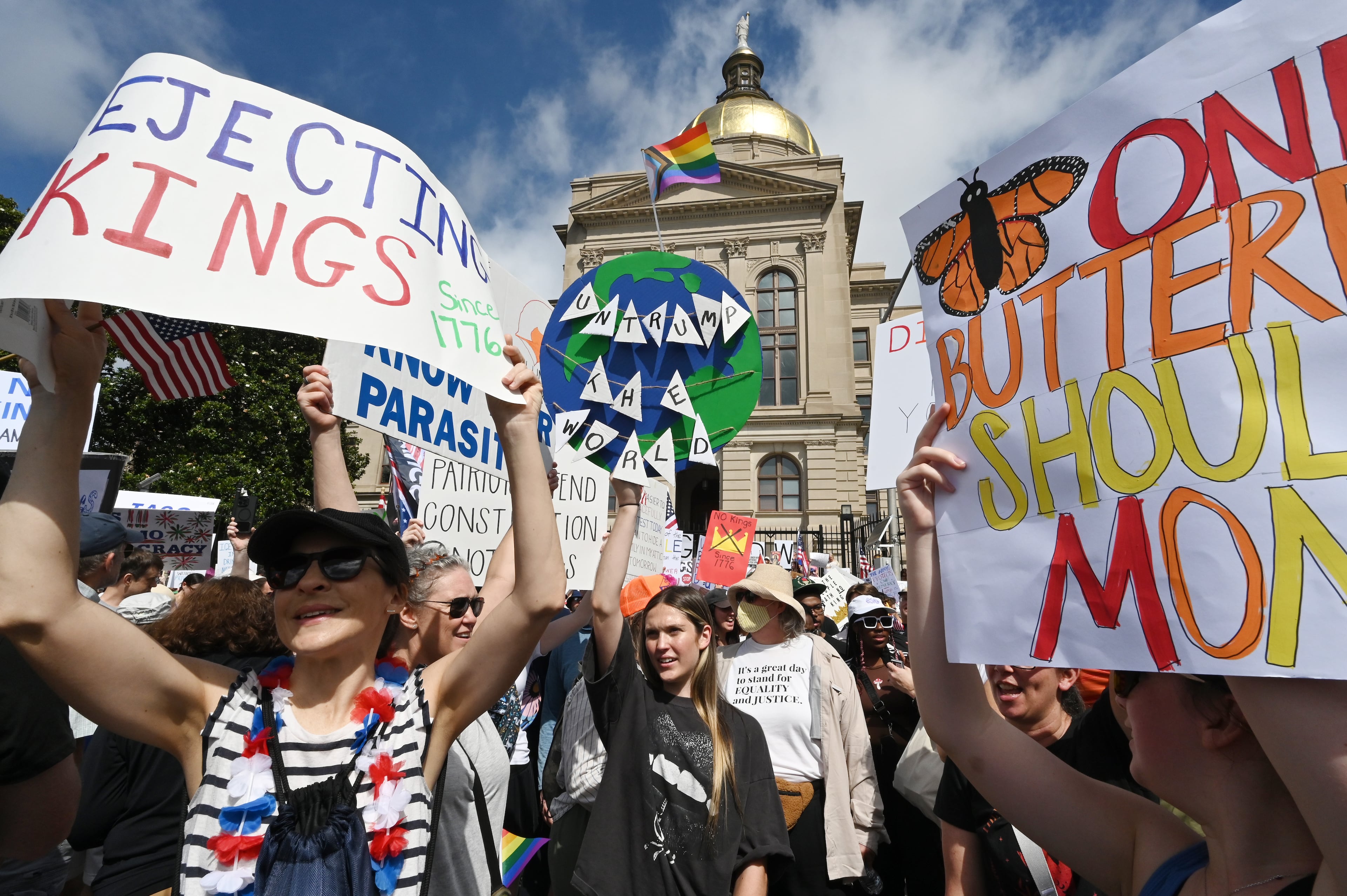 Demonstrators hold signs outside the Georgia Capitol during a "No Kings" protest to oppose Trump’s immigration policies, Saturday, June 14, 2025, in Atlanta. (Hyosub Shin / AJC)