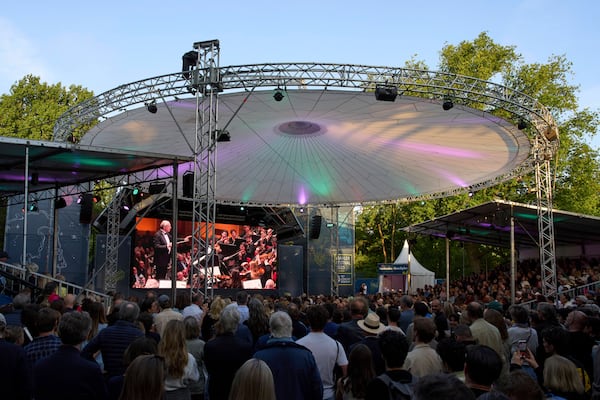 People in Vondelpark watch a video transmission of Ivan Fischer conducting the Budapest Festival Orchestra and the Netherlands Radio Choir performing Mahler's Symphony nr. 2 in the Concertgebouw in Amsterdam, Netherlands, Saturday, May 10, 2025. (AP Photo/Peter Dejong)