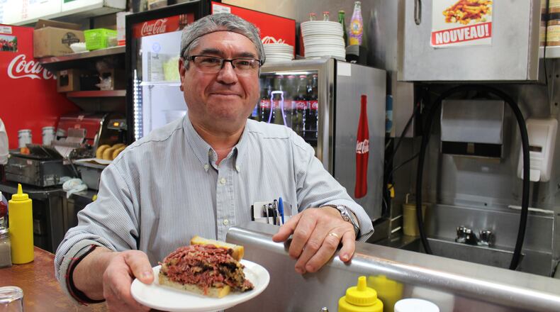 Joao Goncalves serves up one of Schwartz’s legendary smoked meat sandwiches — a half, actually — just as servers have done here since 1928. (Alan Solomon/Chicago Tribune/TNS)